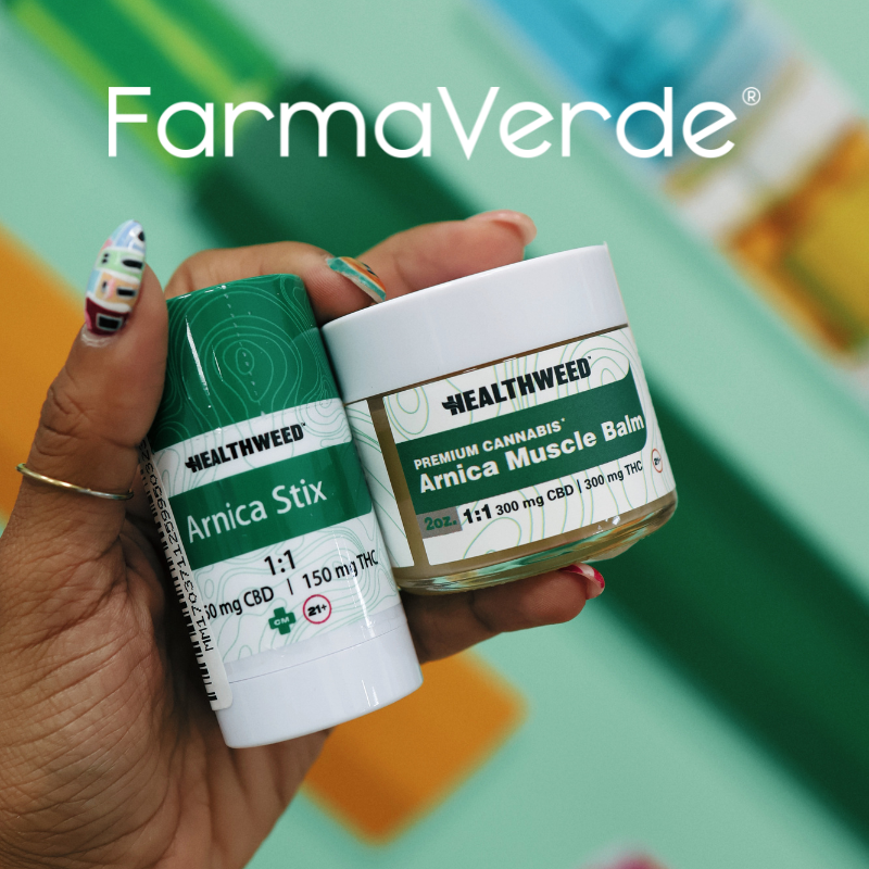 "Mano sosteniendo productos HealthWeed Arnica Stick y Arnica Muscle Rub en un dispensario FarmaVerde en Puerto Rico."